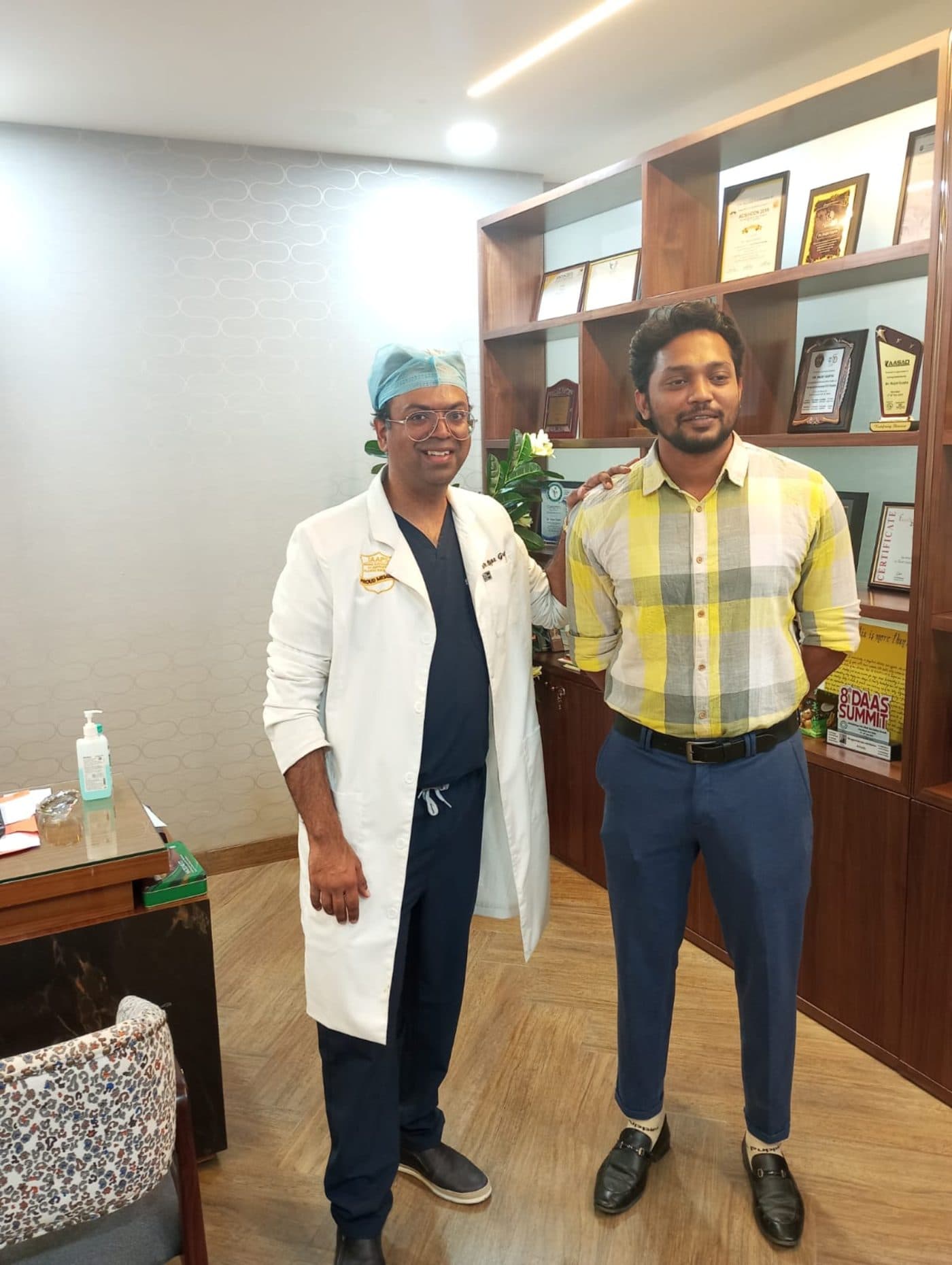 Dr. Dinesh Kumar at the clinic, with awards and certifications in the background